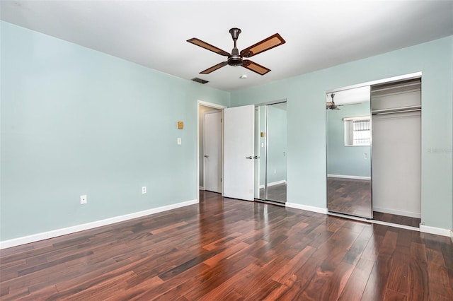 unfurnished bedroom featuring multiple closets, visible vents, ceiling fan, wood finished floors, and baseboards