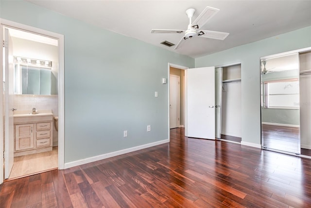 unfurnished bedroom with visible vents, wood finished floors, two closets, and baseboards