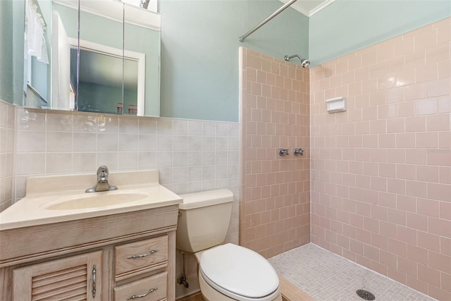 full bathroom featuring a tile shower, tile walls, toilet, and vanity