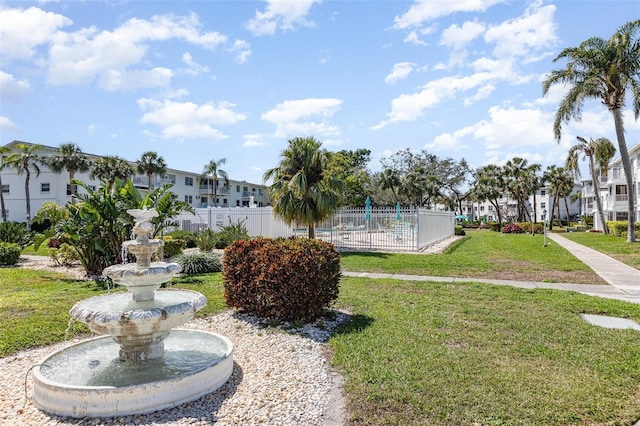 surrounding community with fence and a yard