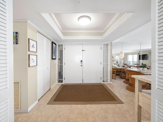 entryway with baseboards, visible vents, a raised ceiling, crown molding, and light tile patterned flooring