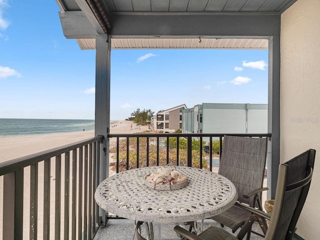 balcony with a water view and a view of the beach