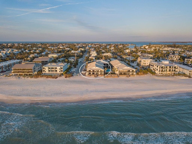 aerial view at dusk featuring a view of the beach and a water view