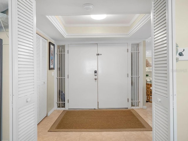 foyer featuring light tile patterned floors, a tray ceiling, and crown molding