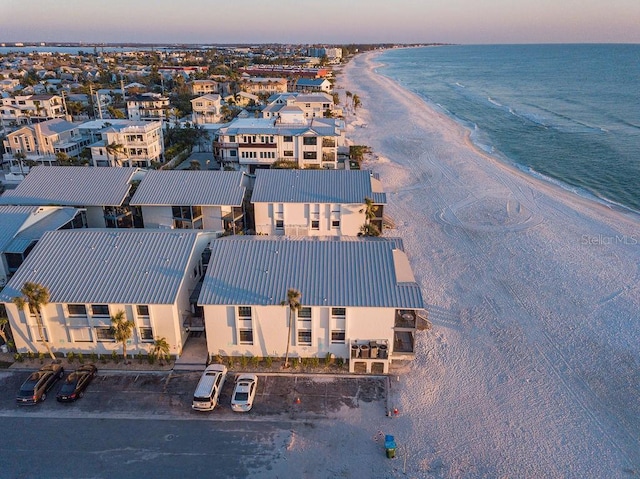 aerial view at dusk with a water view and a view of the beach