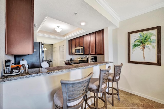 kitchen with a peninsula, appliances with stainless steel finishes, a kitchen breakfast bar, and ornamental molding