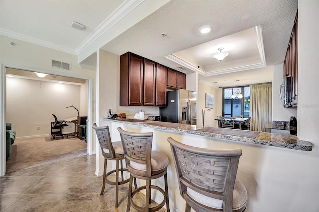 kitchen with visible vents, a raised ceiling, appliances with stainless steel finishes, a peninsula, and light stone countertops