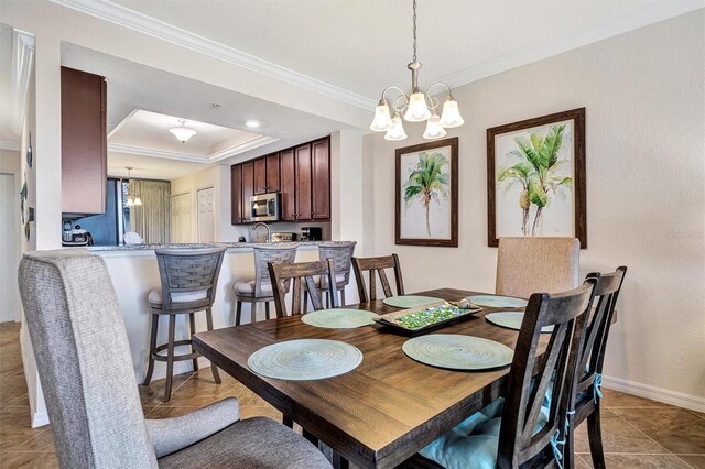 dining space with ornamental molding, a tray ceiling, baseboards, and an inviting chandelier