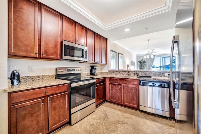 kitchen with light stone counters, crown molding, appliances with stainless steel finishes, a tray ceiling, and an inviting chandelier