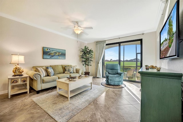 living area with baseboards, ornamental molding, and a ceiling fan