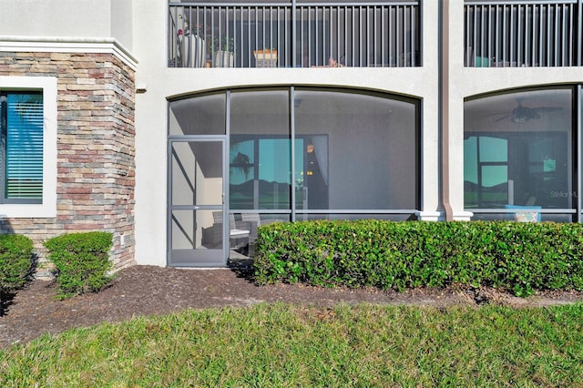 property entrance featuring stone siding and stucco siding