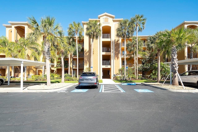 view of building exterior with covered and uncovered parking