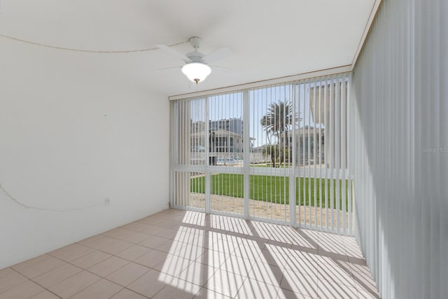 interior space featuring expansive windows, light tile patterned flooring, and a ceiling fan