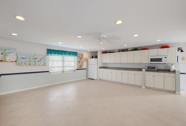 kitchen featuring dark countertops, recessed lighting, white cabinets, white appliances, and baseboards