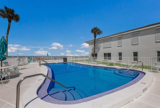 pool with a patio area and fence