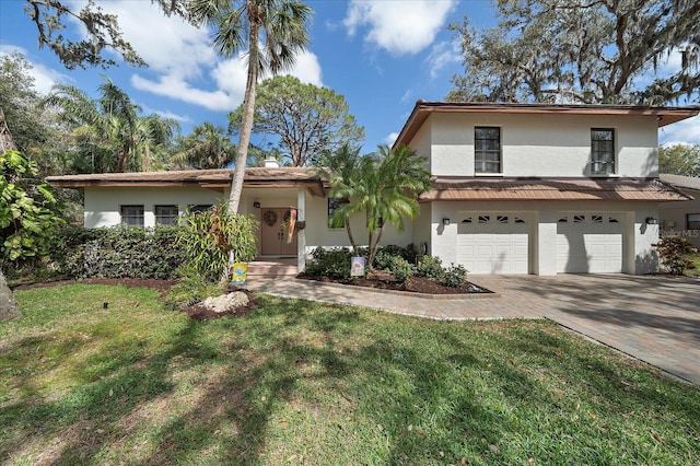 view of front of property with a front lawn, decorative driveway, an attached garage, and stucco siding