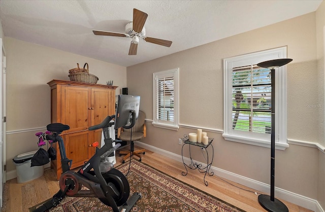 exercise room featuring a ceiling fan, baseboards, and wood finished floors