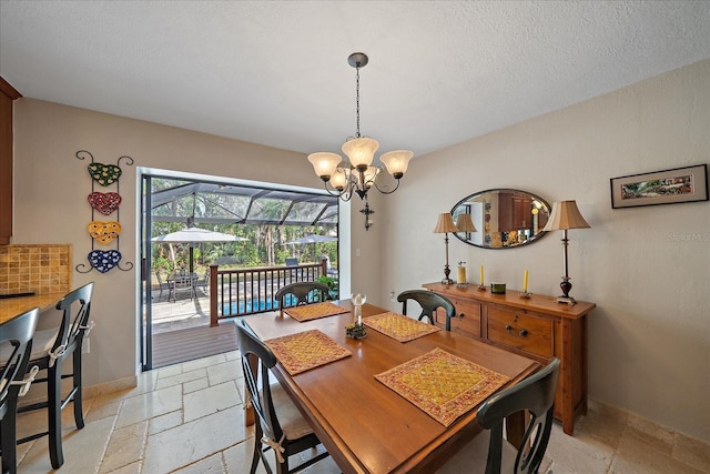 dining room with an inviting chandelier, stone tile floors, baseboards, and a textured ceiling