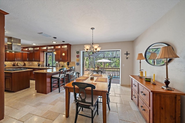 dining area featuring a notable chandelier, stone tile floors, visible vents, a textured ceiling, and baseboards