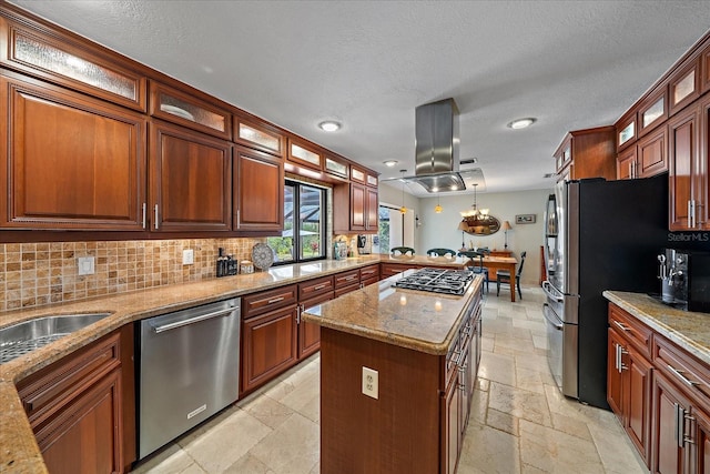 kitchen featuring stone tile floors, decorative backsplash, a peninsula, island exhaust hood, and stainless steel appliances