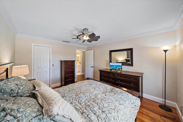 bedroom featuring a closet, visible vents, ornamental molding, wood finished floors, and baseboards