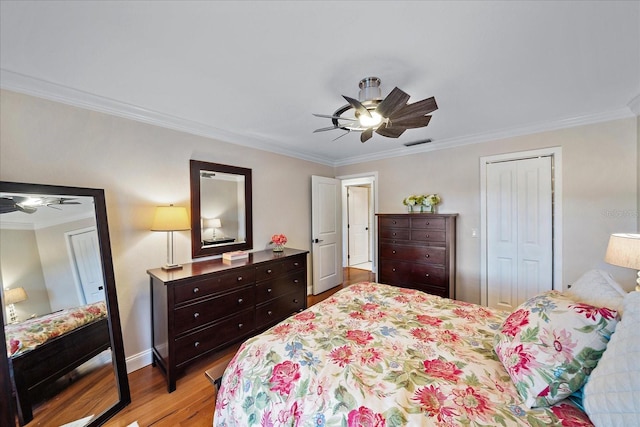 bedroom with a closet, visible vents, light wood-style flooring, ornamental molding, and ceiling fan