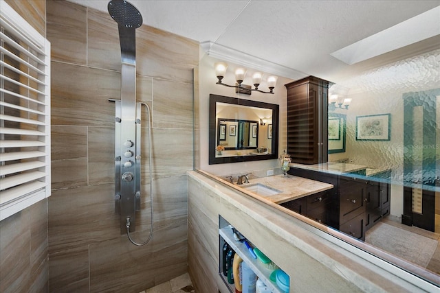 full bathroom featuring a textured ceiling, a tile shower, vanity, and crown molding