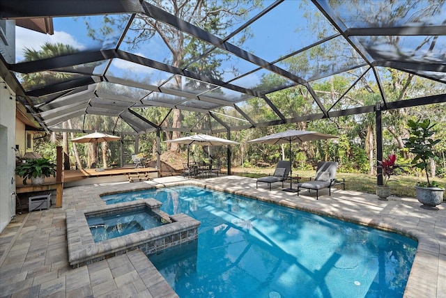 view of pool with a patio, glass enclosure, and a pool with connected hot tub