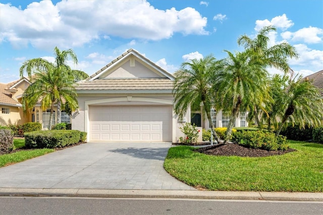 ranch-style home with driveway, a garage, stucco siding, a tiled roof, and a front yard