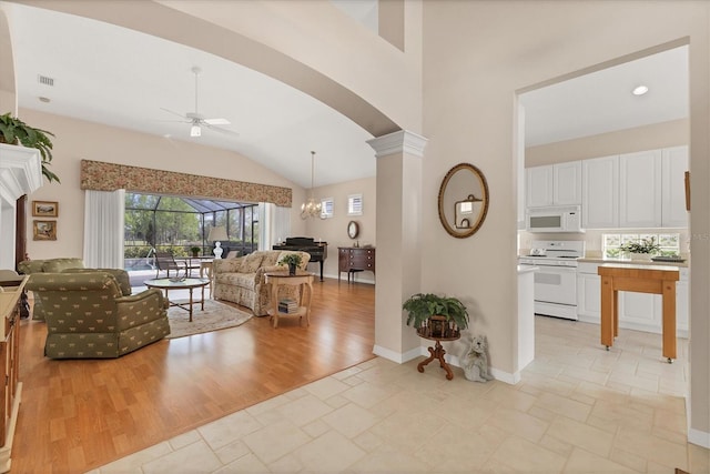 living room with arched walkways, visible vents, light wood-style floors, ornate columns, and ceiling fan with notable chandelier