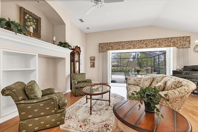 living area featuring baseboards, visible vents, lofted ceiling, ceiling fan, and wood finished floors