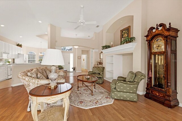 living room featuring light wood-style floors, arched walkways, a ceiling fan, and recessed lighting