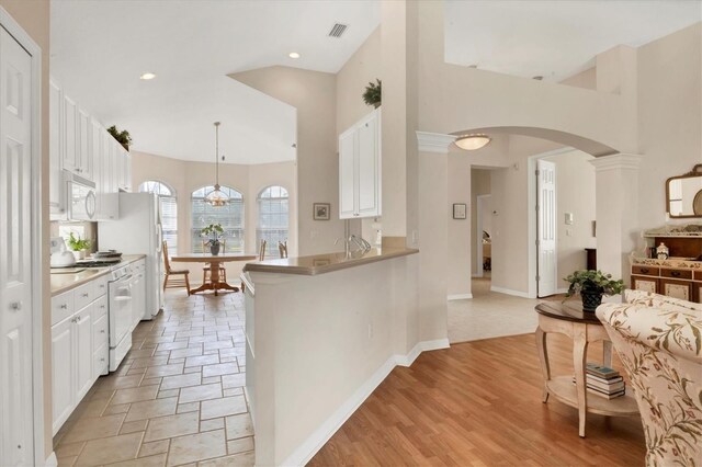 kitchen with white appliances, visible vents, a peninsula, white cabinetry, and pendant lighting