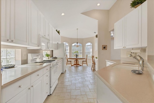 kitchen with white appliances, white cabinets, light countertops, and decorative light fixtures