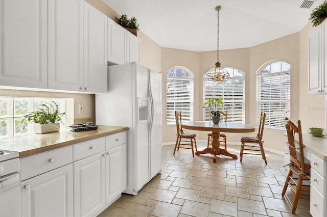 kitchen with white cabinets, range, light countertops, white fridge with ice dispenser, and pendant lighting