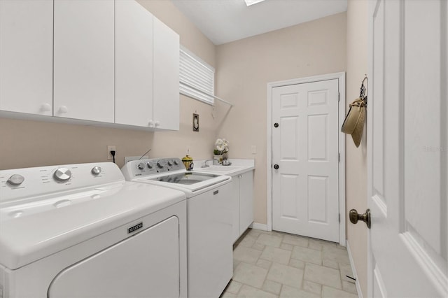 laundry room featuring washing machine and dryer, a sink, baseboards, cabinet space, and stone finish floor