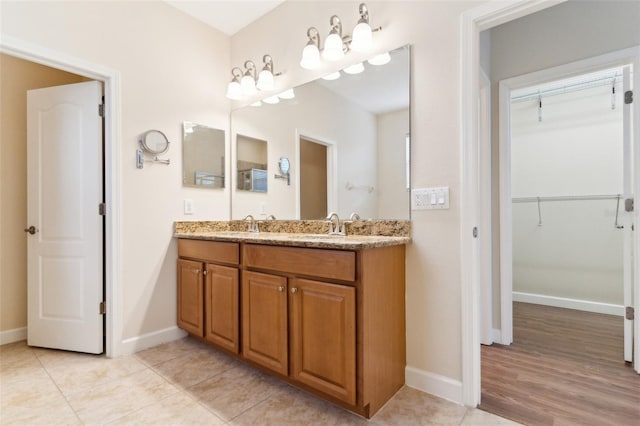 bathroom featuring tile patterned floors, a spacious closet, baseboards, and double vanity