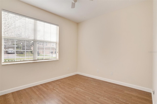 empty room with baseboards, ceiling fan, and light wood-style floors