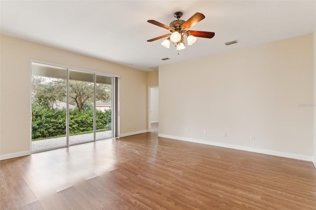 unfurnished room with ceiling fan, wood finished floors, visible vents, and baseboards