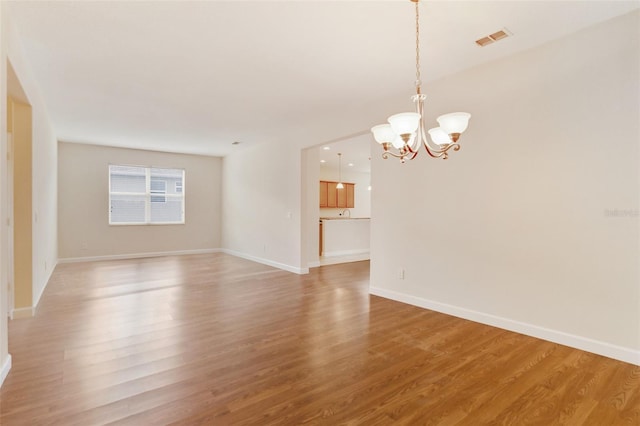 unfurnished living room with light wood-style floors, baseboards, visible vents, and a chandelier