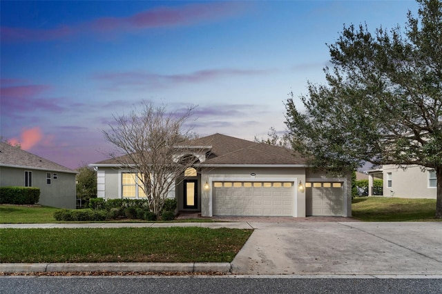 view of front of home featuring concrete driveway, a front yard, an attached garage, and stucco siding