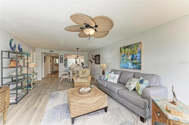 living area featuring light wood finished floors, ceiling fan, and visible vents