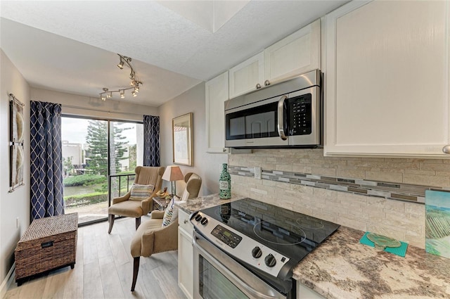 kitchen featuring stainless steel appliances, white cabinetry, backsplash, and light stone counters