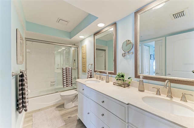 bathroom featuring enclosed tub / shower combo, visible vents, and a sink