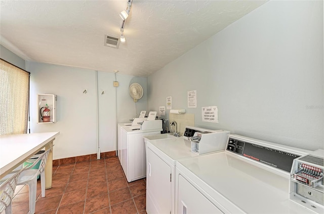 shared laundry area with a textured ceiling, track lighting, visible vents, and washer and dryer