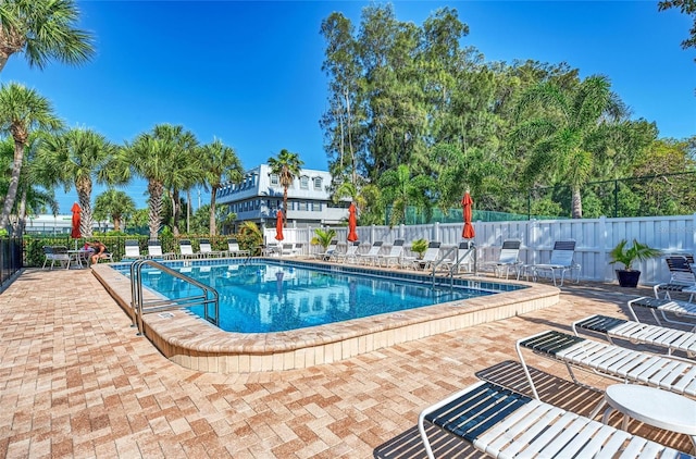 community pool with a patio area and fence