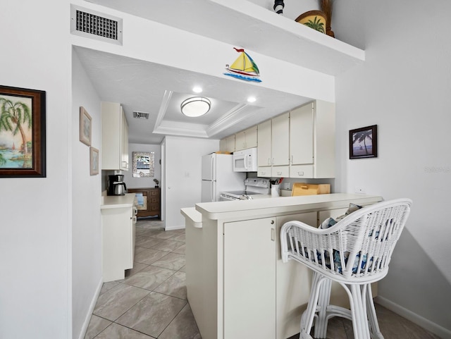 4621 Gulf Of Mexico Dr Unit 19B, Longboat Key, FL 34228 - kitchen featuring white appliances, a peninsula, light countertops, a raised ceiling, and a kitchen breakfast bar