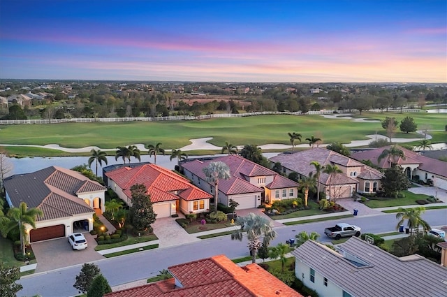 aerial view at dusk featuring view of golf course and a residential view