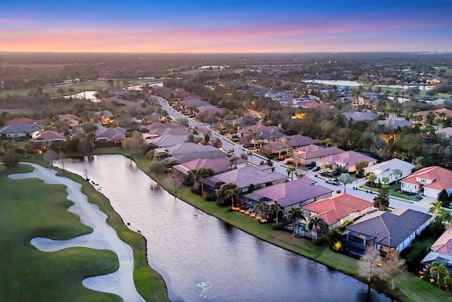 aerial view at dusk with a water view and a residential view