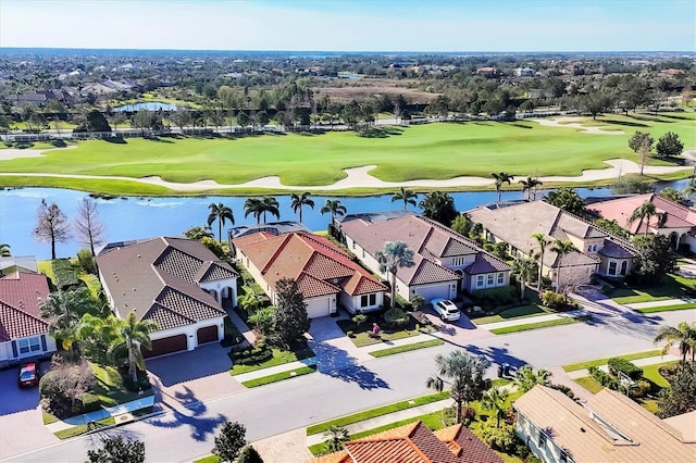 drone / aerial view featuring golf course view, a water view, and a residential view